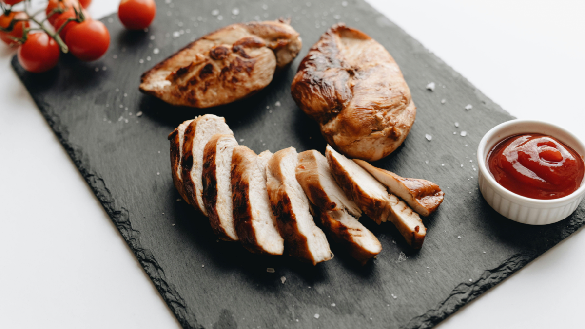 Freshly sliced rotisserie chicken on a slate tray