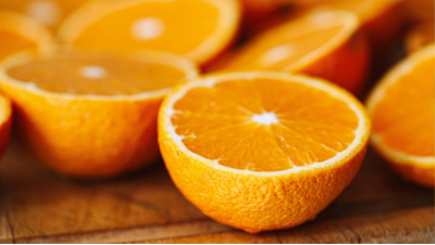 Glass of cold-pressed orange juice beside freshly cut oranges